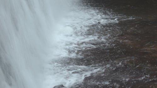 Powerful Waterfall Rushing Over Rocks into River