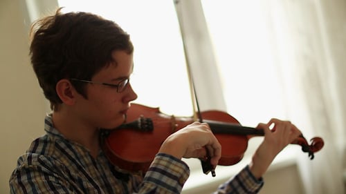 Teenage Boy Plays Violin at Home During Daytime