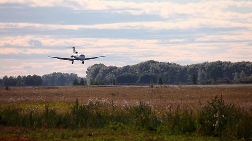 Airplane Landing on Grassy Runway in Rural Setting