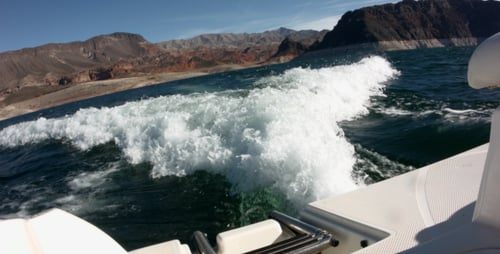 Boat Speeding on Teal Water with Mountain Backdrop