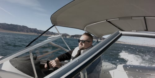 Man Driving Speedboat Across Lake on Sunny Day