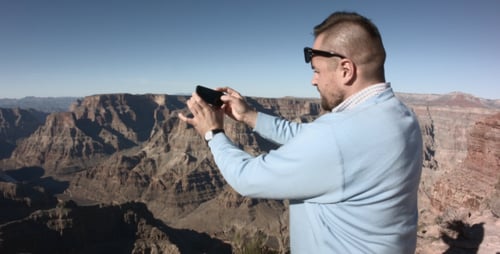 Man Taking Pictures of Canyon Landscape