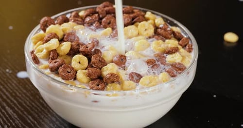 Milk Being Poured into Donut Cereal in Bowl