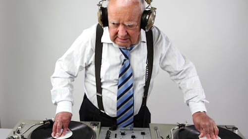 Elderly Person Using Sound Mixing Board And Headphones