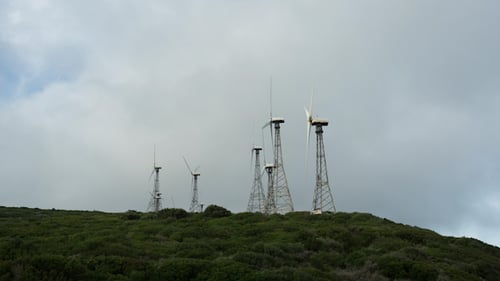 Wind Turbines Spinning Atop Green Hill