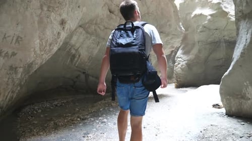 Unrecognizable Young Man with Backpack Walking Across Narrow Canyon