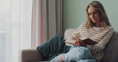 Woman Reading Book on Couch in Living Room