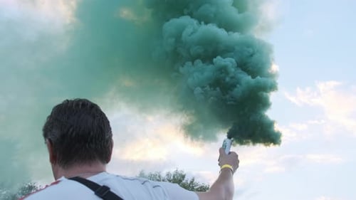 Man Holding a Teal Smoke Grenade Outdoors