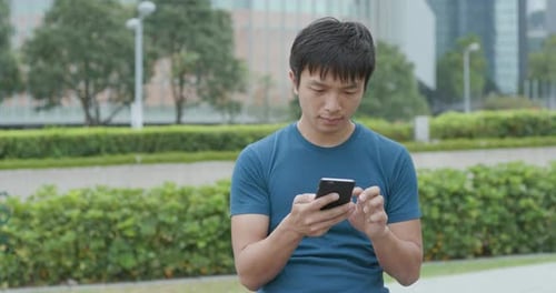 Young Adult Using Smartphone in City Park