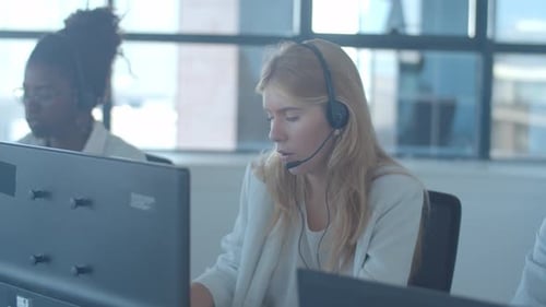 Fokussiertes, blondes Bediener-Headset nimmt Anrufe entgegen