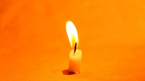 Candle Burning Brightly on Orange Background