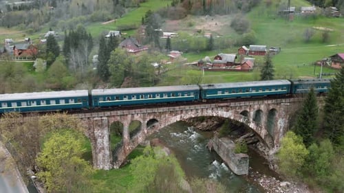 Train passing over bridge. Passenger train crossing old viaduct bridge over river.