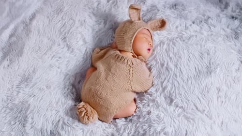 Vue arrière : nouveau-né heureux vêtu d'un joli costume de lapin couché et endormi