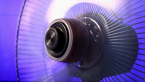 Spinning household fan on purple background