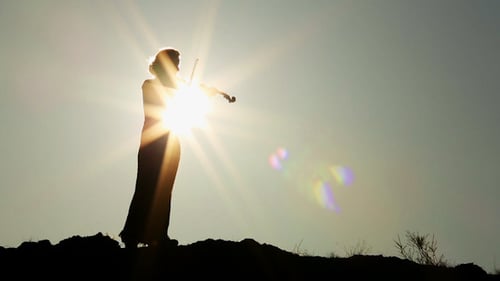 Silhouette of Woman Playing Violin at Sunrise