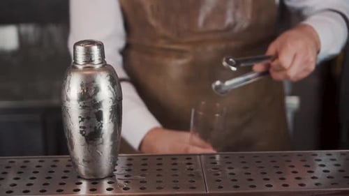 Bartender Adds Ice To Glass with Tongs
