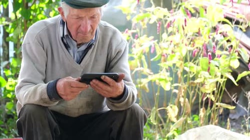 Senior Man Using Smartphone Outdoors in Garden