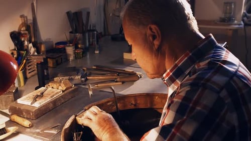 Man Carefully Crafting Metal in Workshop