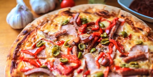 Fresh Pizza Topped with Ham, Peppers, and Olives