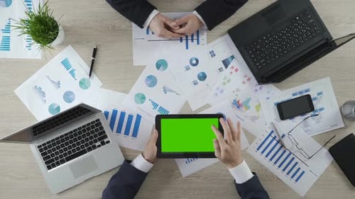 Mann hält Tablet mit Greenscreen und zeigt dem Partner Unternehmenspräsentation