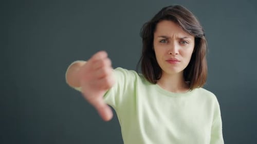 Young Woman Gives Thumbs Down Gesture to Camera