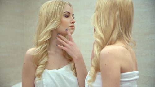 Woman in Towel Examines Reflection in Mirror