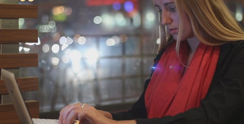 Young Woman Types on Laptop at Night in City