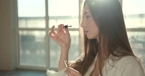 Pretty European Woman Applying Maskara at Studio