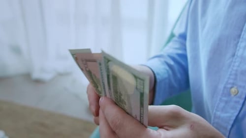 Man Counting US Dollar Bills in Hand