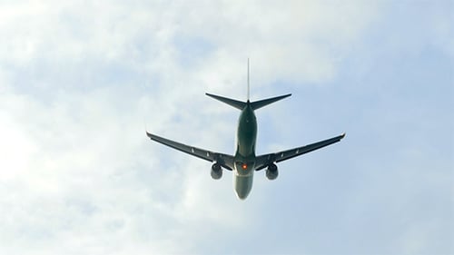 Commercial Airplane Ascending Through Cloudy Daytime Sky