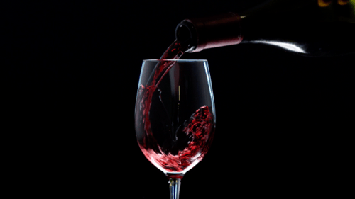 Pouring Wine into Wine Glass on Black Background