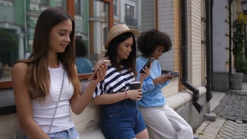 Three Friends Use Phones on City Street
