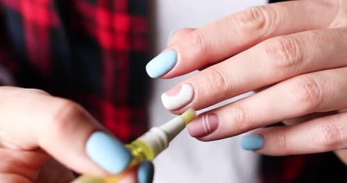 Closeup of female hands with beautiful manicure applying oil to cuticles of fingers