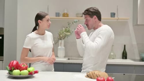 Woman Gives Mug to Man in Kitchen