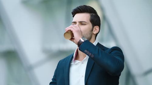 Man Drinks Coffee and Checks Phone in City