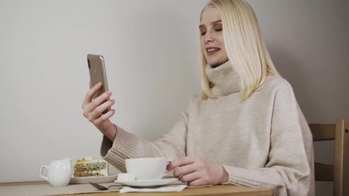 Girl in a Coffee Shop Talking By Video Call and Drinking Coffee