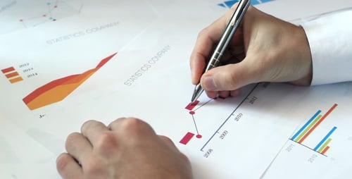 Man Analyzing Business Data with Pen in Office
