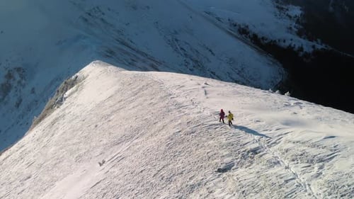 Mountaineers Walking on Snowy Mountain Ridge