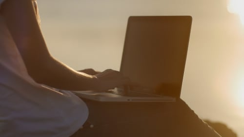 Person Typing on Laptop in Golden Light