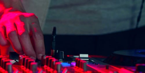 DJ Mixing Music with Console Under Red and Blue Lights