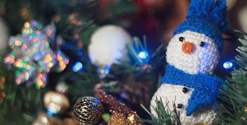 Crocheted Snowman Surrounded by Christmas Decorations and Lights