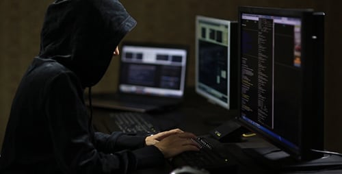 Hacker in Hood Typing on Keyboard