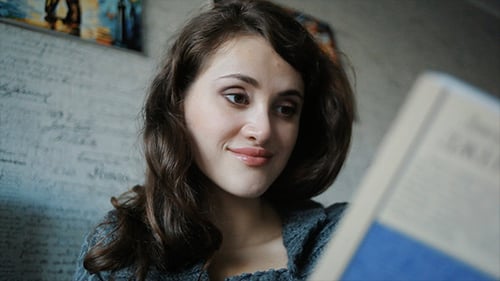 Young Woman Reading Book Sitting On The Sofa