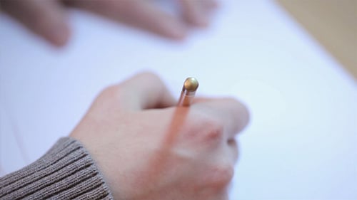 Close-up of Hand Writing on Paper with Pencil
