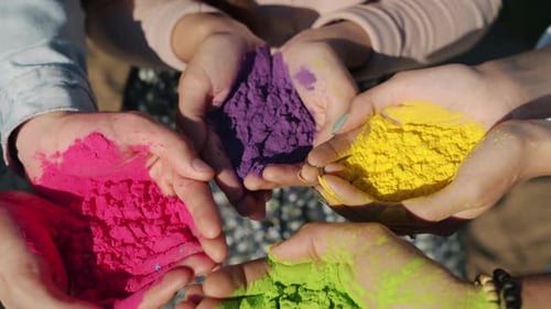 Nahaufnahme menschlicher Hände, die bunte Pulverfarbe Gulal für die Holi-Festivalzeremonie draußen halten
