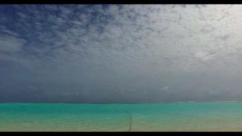 Luftbild über der Landschaft eines ruhigen touristischen Strandurlaubs vor blauem Meer und weißem Sandhintergrund eines