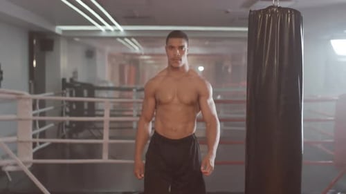 Boxen, Athletic Man Fighter trainiert im Boxstudio, ein muskulöser Mann nimmt eine kämpfende Haltung ein und schaut