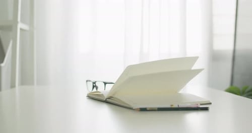 Books pages turning by wind on table in the office room at home.