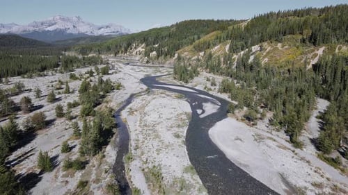 Long, dry valley dividing a vast boreal forest landscape with the majestic Rocky Mountains in the ba