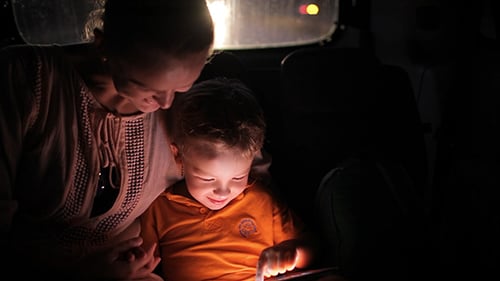 Woman and Child Use Tablet in Car at Night